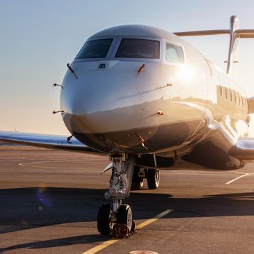 Private jet parked on a sunlit runway at sunset.