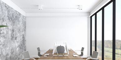 Modern office space with wooden desks, ergonomic chairs, and large windows overlooking greenery.