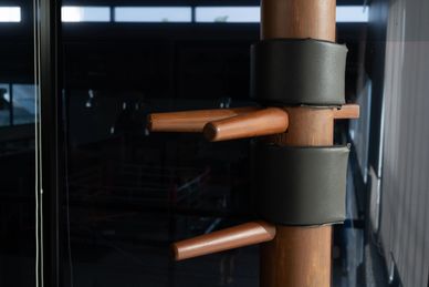 Wooden Wing Chun dummy with padded arms in a training room.