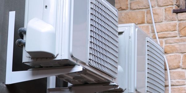 Two white air conditioning units mounted on an exterior wall.