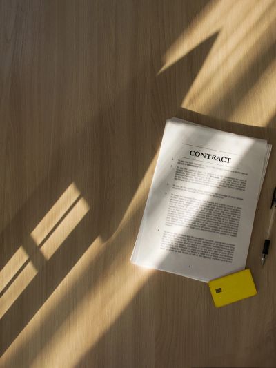 Contract document on a wooden table with sunlight and shadows.