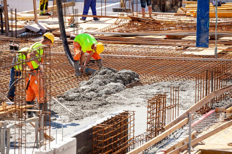 Workers pouring concrete. Concrete pouring on the construction site. Concrete pump. Reinforcement steel, reinforcing bar, rebar, foundation plate. Unrecognizable people