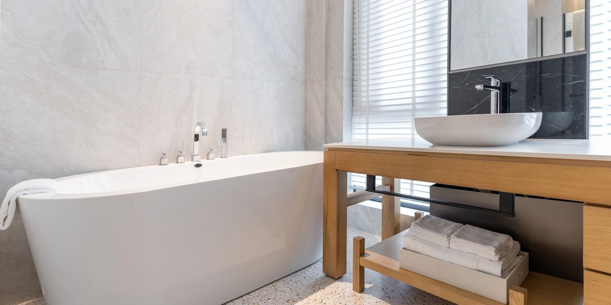 Modern bathroom with a white freestanding tub and wooden vanity with vessel sink.