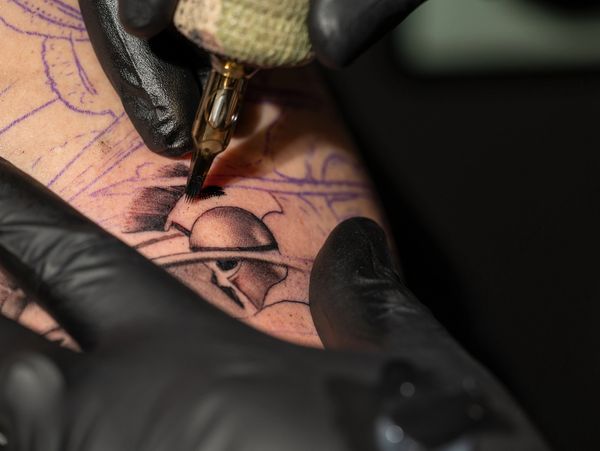 Close-up of a tattoo artist shading a Spartan helmet tattoo.