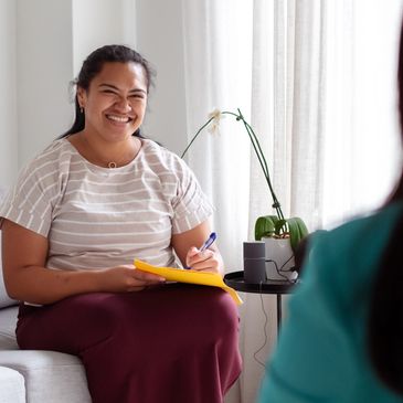 Smiling woman taking notes during a conversation in a cozy room.