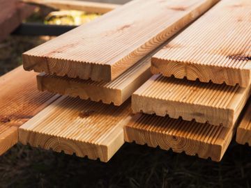 Planches de bois rainurées empilées.