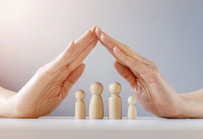 Pointed hands together over a wooden family figures representing family therapy