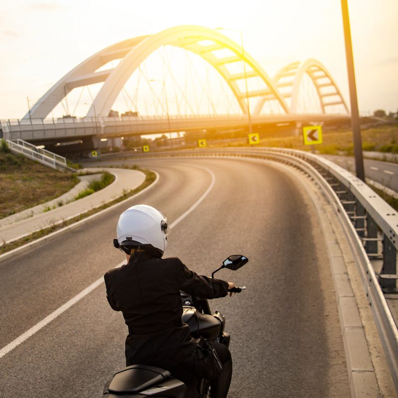 Young woman riding a motorcycle on a road. About 25 years old, Caucasian female.