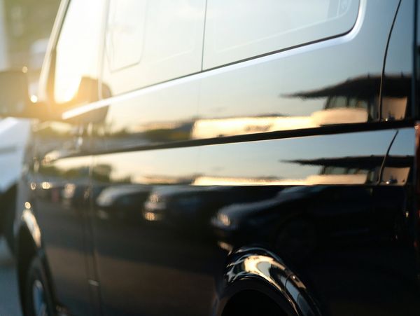 Reflection of sunset on the side of a shiny black vehicle.