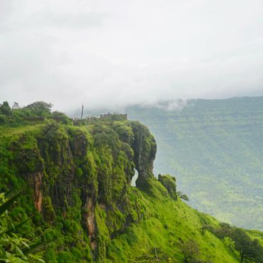 Lush green cliffs with misty mountains in the background.