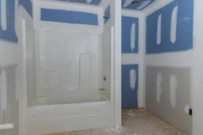 Partially finished bathroom with a white bathtub and drywall in progress.