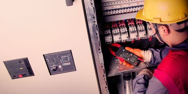 Electrician measuring current in electrical panel.