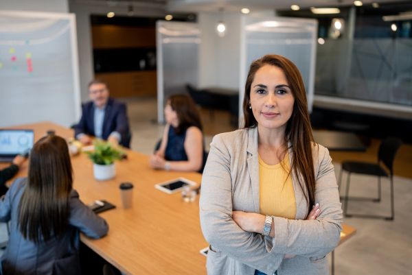Professional woman standing confidently in office meeting room.