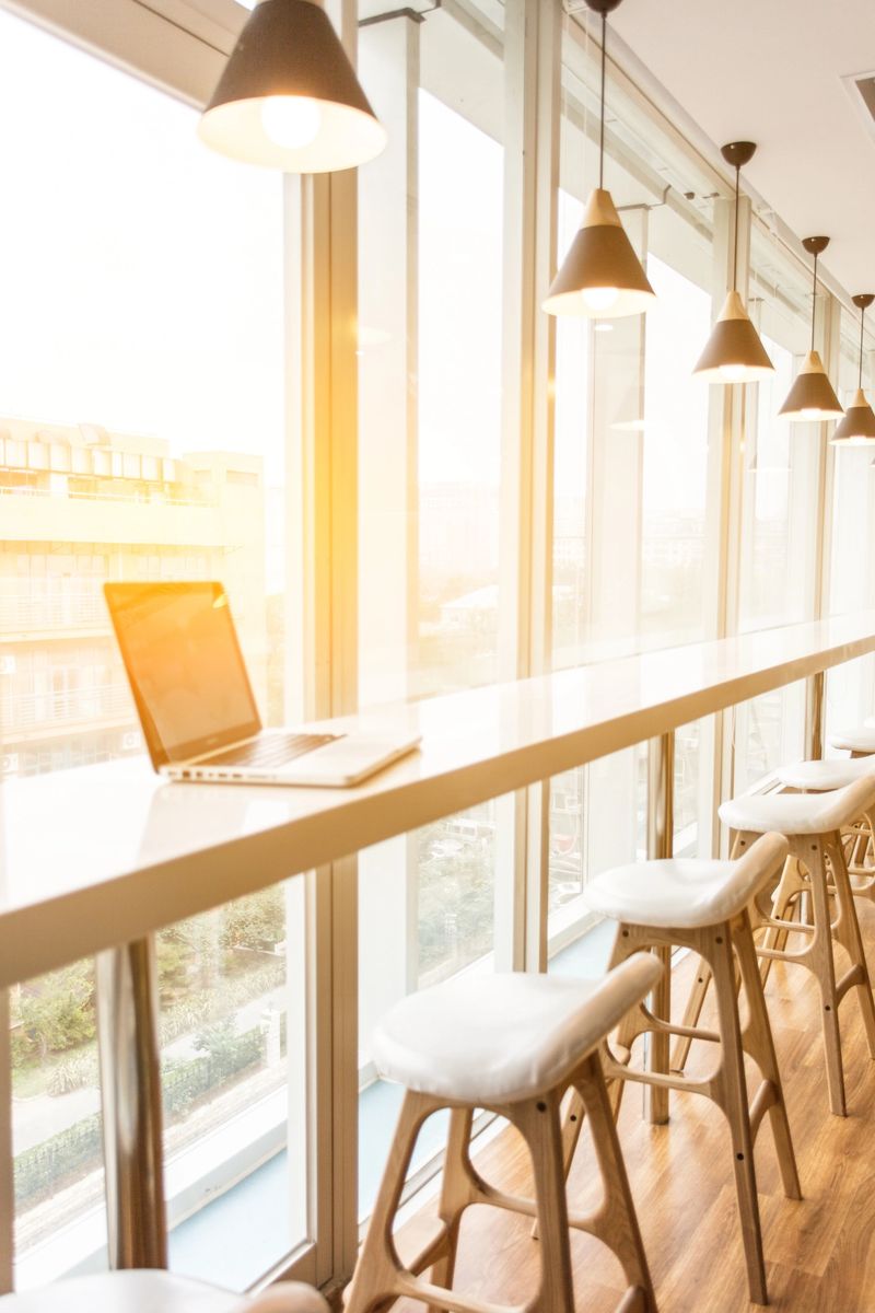New modern office room in building with wooden corporate business table closeup by glass window and row of high stools