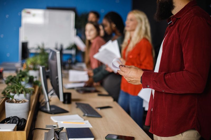Business colleagues are discussing company performance, pointing at charts and graphs displayed on a tablet during a productive meeting in the office