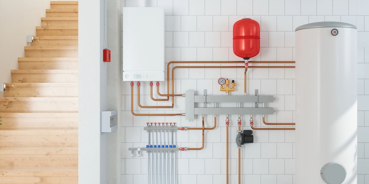 Modern heating system with copper pipes and a white storage tank beside wooden stairs.