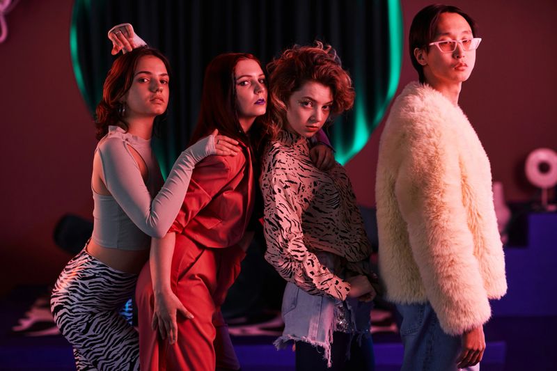 Side view portrait of dance crew looking at camera in nightclub lit by red neon light