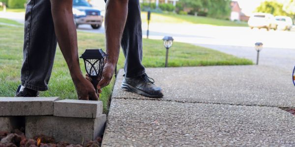 Person installing solar garden lights along driveway.