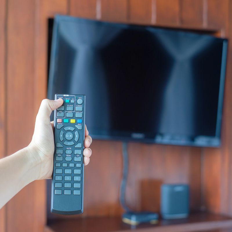 hand using remote controller for adjust Smart TV inside the modern room at home or luxury hotel