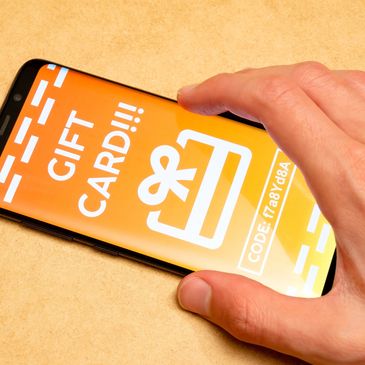 Hand holding phone with gift card on screen.