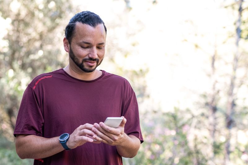 A happy and confident sportsman consults his investments on his smartphone
