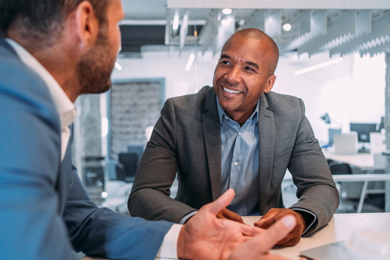 Two businessmen engaged in a positive conversation at a modern office.