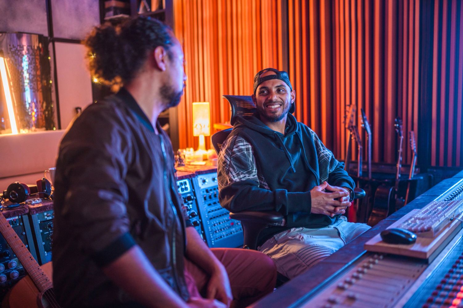Two men chatting in a vibrant music studio with instruments.