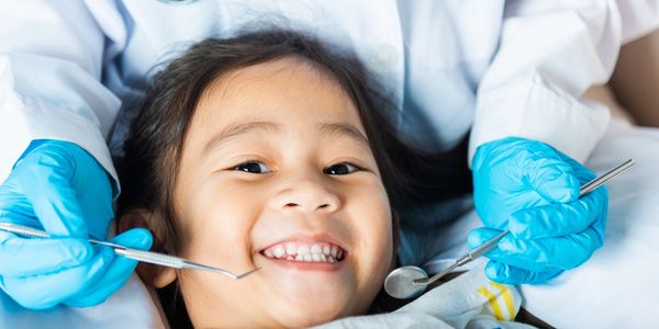 Smiling child at the dentist with dental tools.