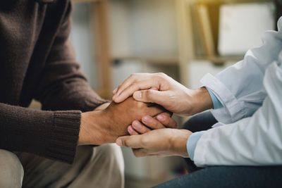 Doctor comforting patient by holding their hands warmly.