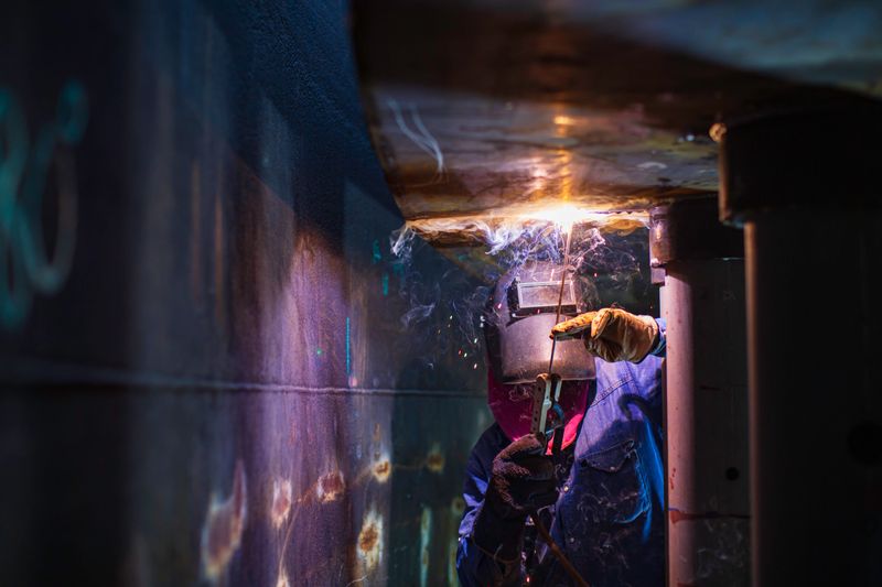 Welding male worker metal arc is part in machinery tank nozzle pipeline construction petroleum oil and gas storage tank inside confined spaces.