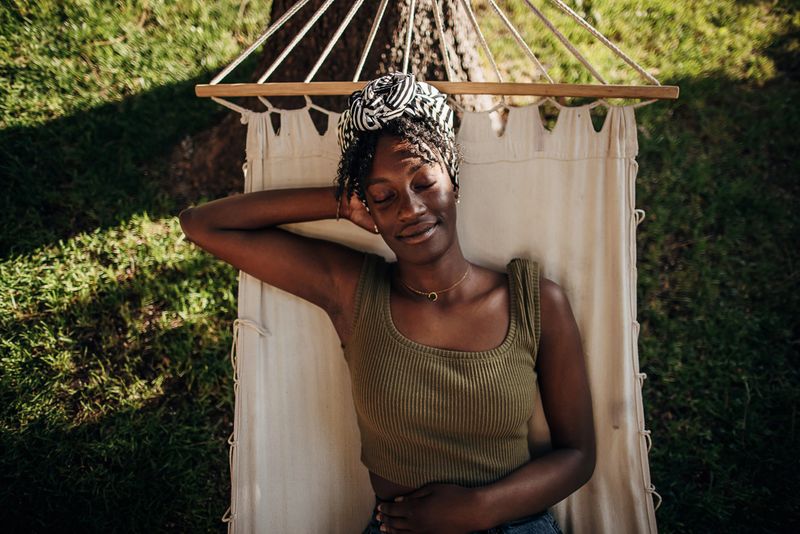 Black woman relaxing in a hammock outdoors in back yard