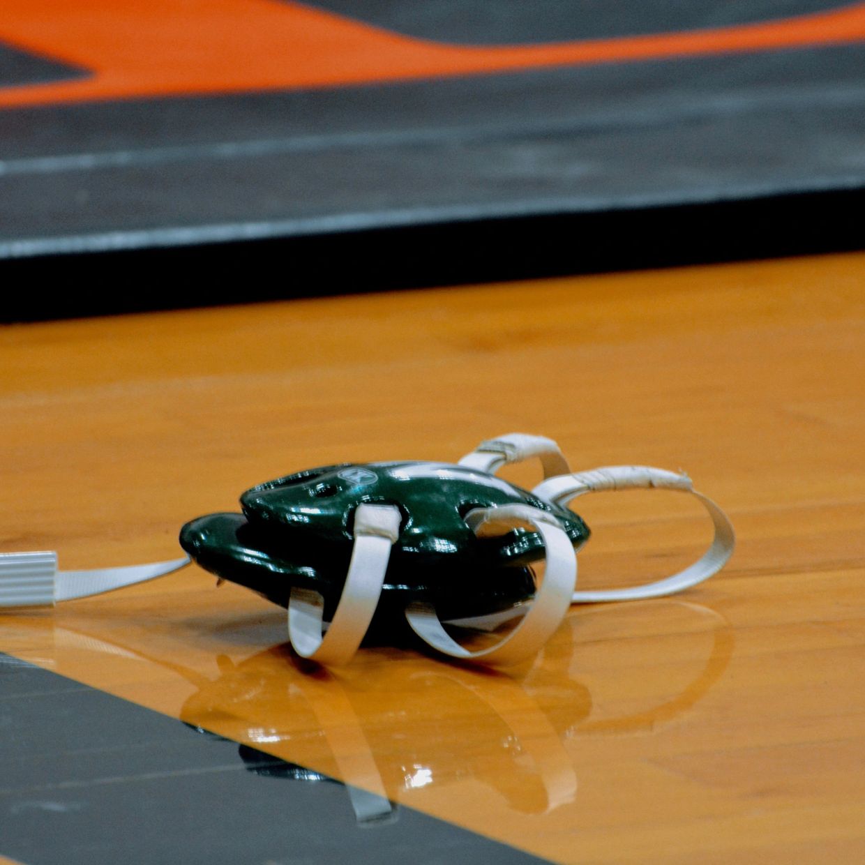 Green wrestling headgear on gym floor.