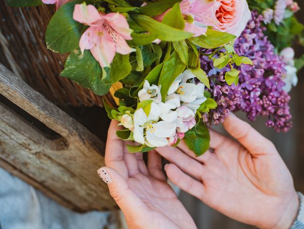 Hands gently holding a bouquet of colorful spring flowers.