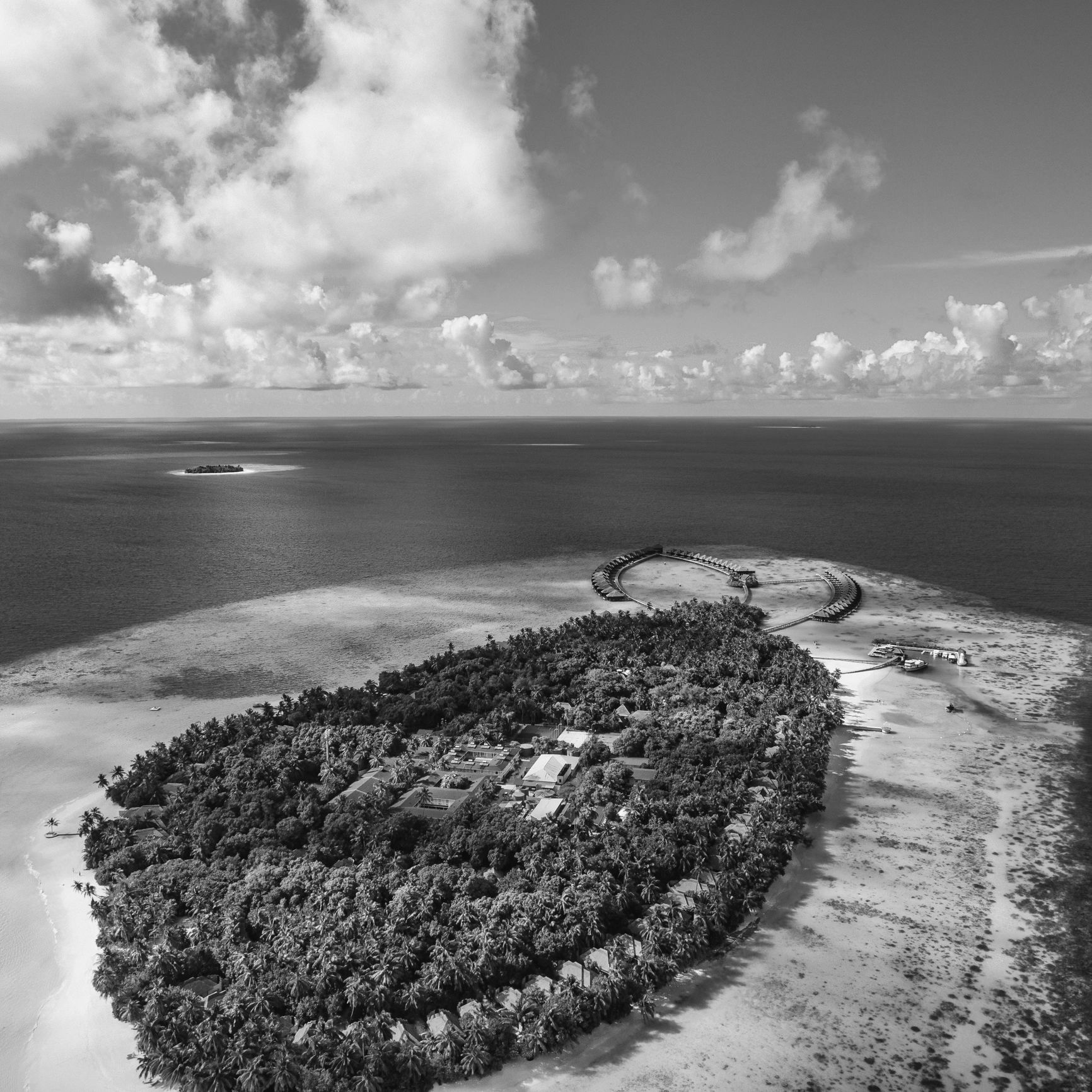 Aerial view of a tropical island resort surrounded by clear blue ocean.