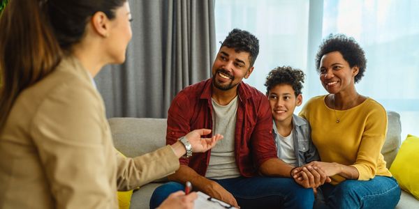 A family happily talking with a counselor in a cozy living room.