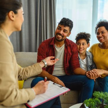 Family discussing with a counselor in a cozy living room setting.
