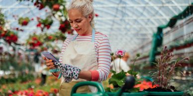 Woman gardener using phone in greenhouse.