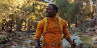 Man hiking in nature with a backpack and walking sticks.