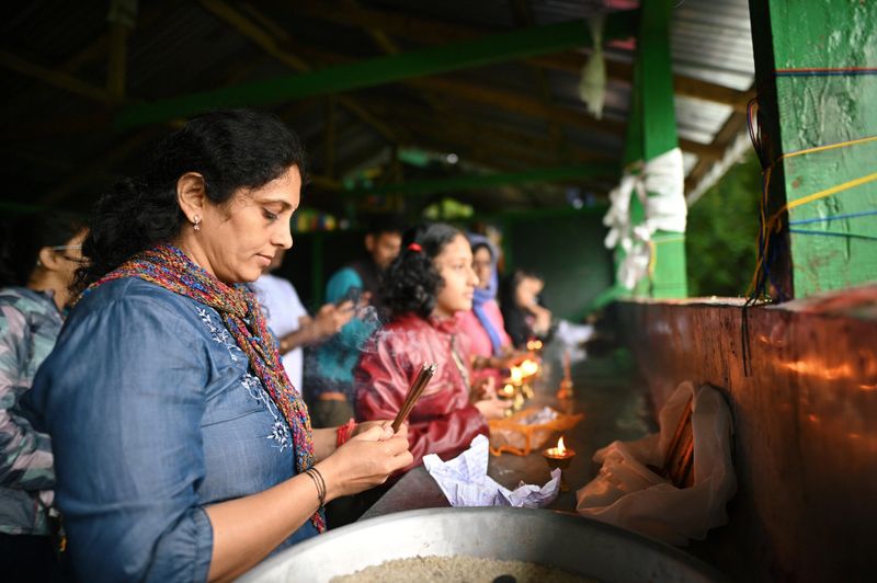 A woman praying by holding lighted incense sticks in her hand at Khecheopalri Lake in West Sikkim