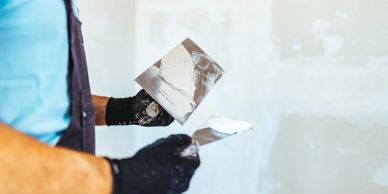 Person applying plaster on a wall with a trowel.