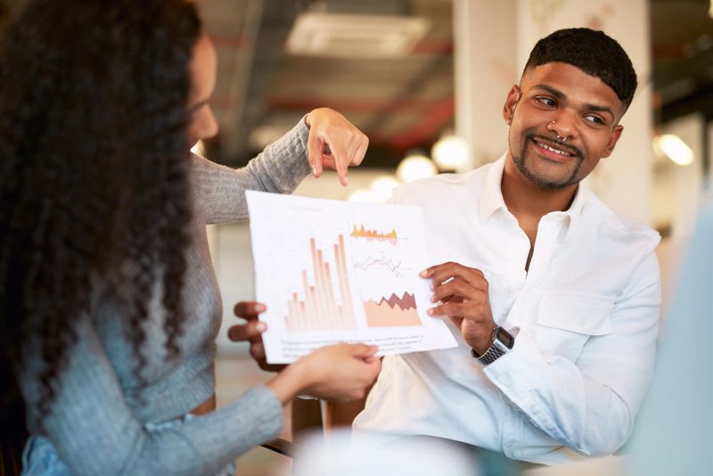 Two people in meeting discussing information on a graph in the office. Business professionals looking confident and analyzing data using graph. Finding the perfect makeup colour pallet blog tutorial