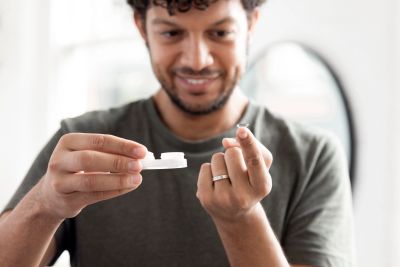 Man holding a contact lens and its case.