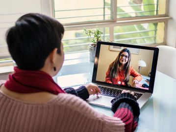 Woman video chatting with a friend on a laptop.