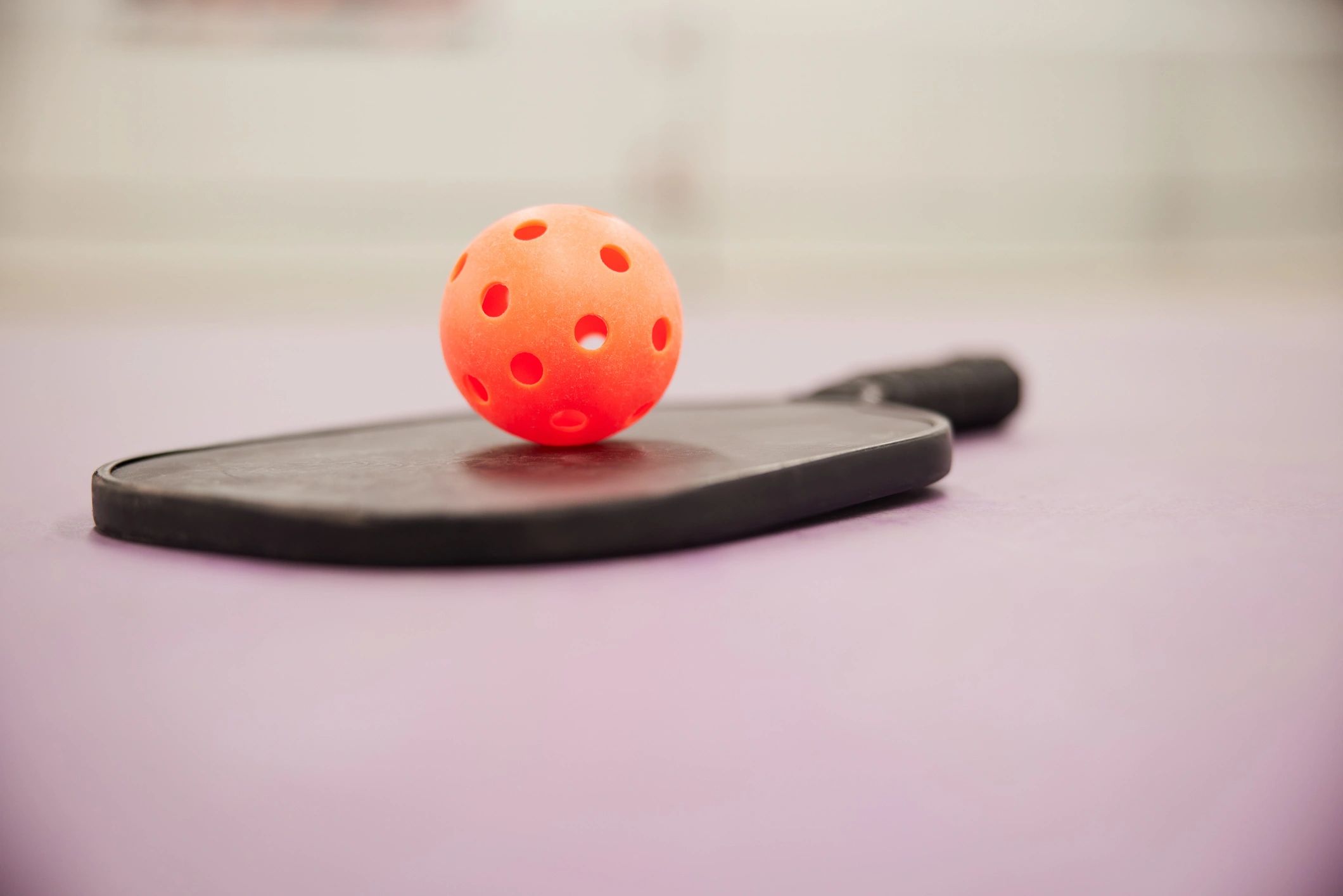 Orange perforated ball on a paddle.