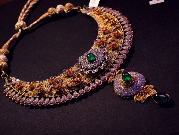 Intricate gold and gemstone necklace with floral designs.