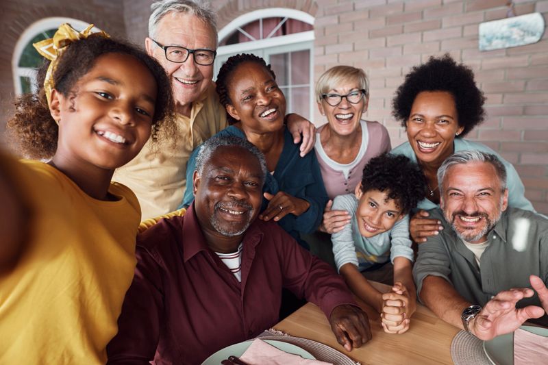 Cheerful multiethnic extended family taking selfie and having fun together while gathering on patio.