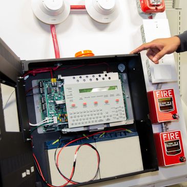 Open fire alarm control panel with connected wiring and devices.