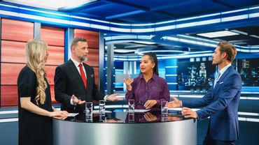 Four professionals engaged in a lively discussion on a modern TV news set.
