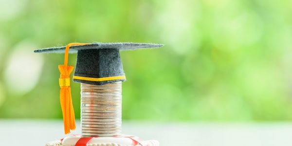 Stack of coins with a graduation cap on a life preserver.