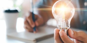 A man writing the notes and hold the bulb on the hand